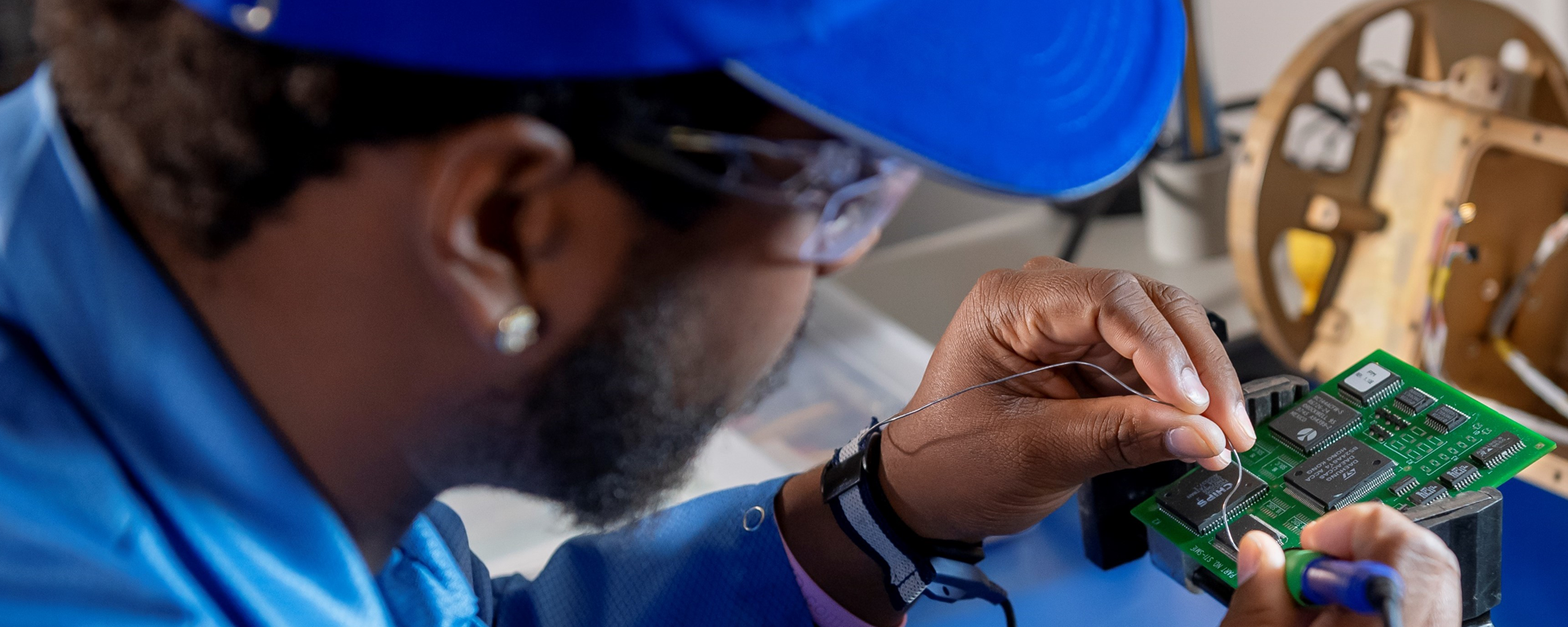 Employee in front of various tools working on a circuit board